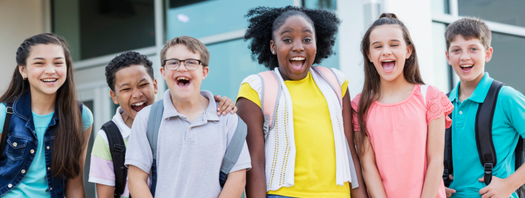 a group of 6 students smile and look at the camera in front of a school building
