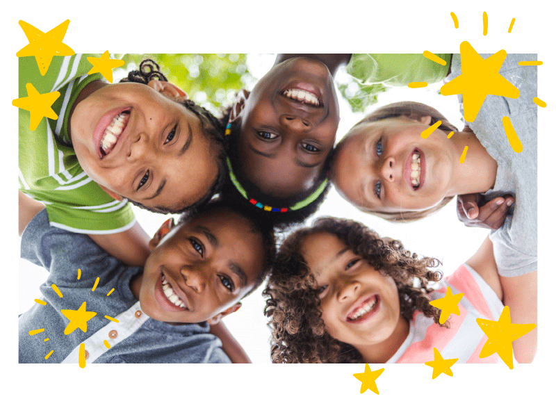 Five kids standing in a circle with their arms on each others' shoulders lean over a camera pointed up at them from below. Stars pop up onto the image as the gif plays.