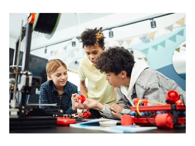 Three older kids lean over a counter examining a model they are building together. Stars pop onto the image as the gif plays.